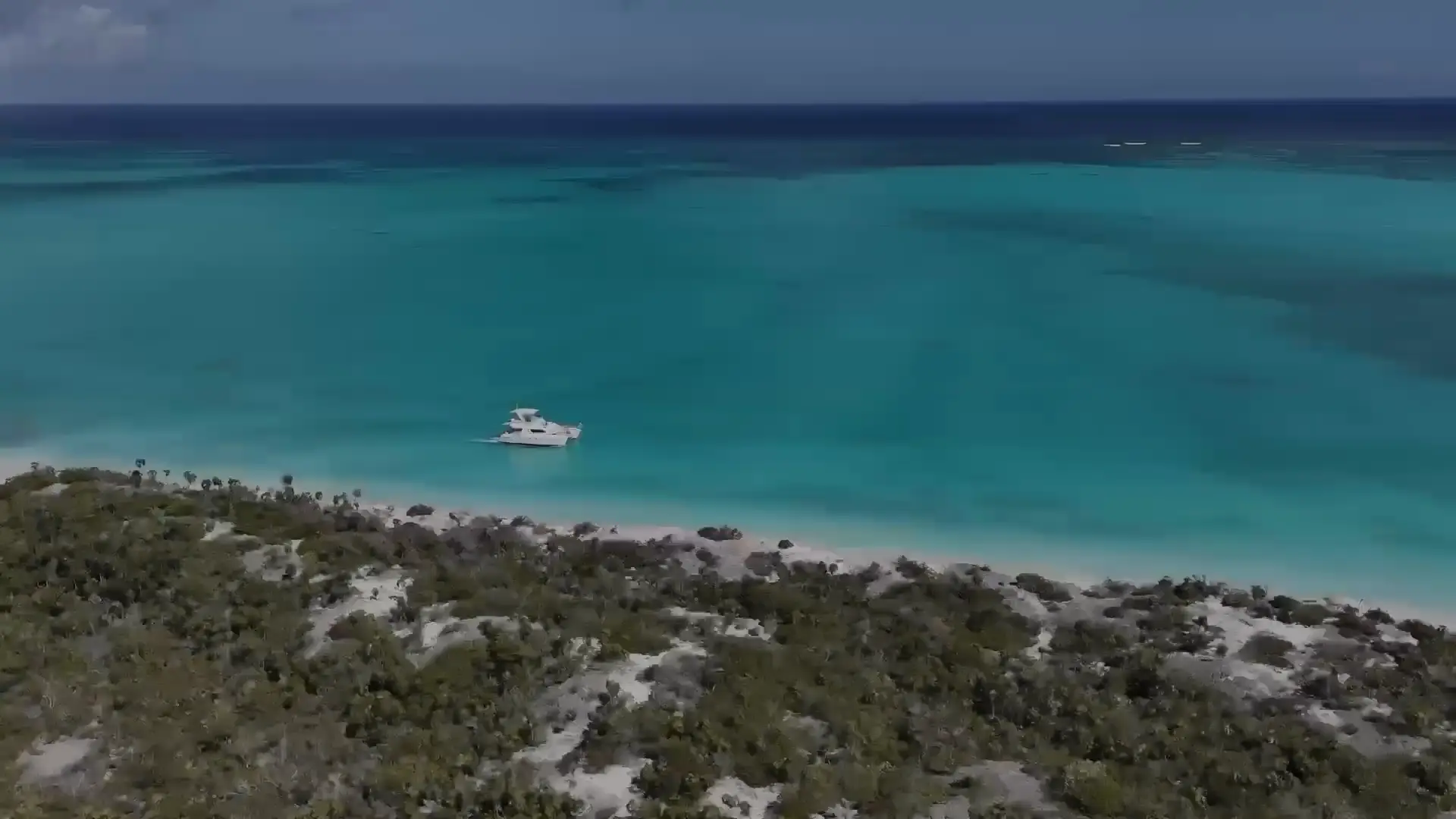 Aerial view of a Big Blue boat off a white beach and turquoise water, from Big Blue's own hero film